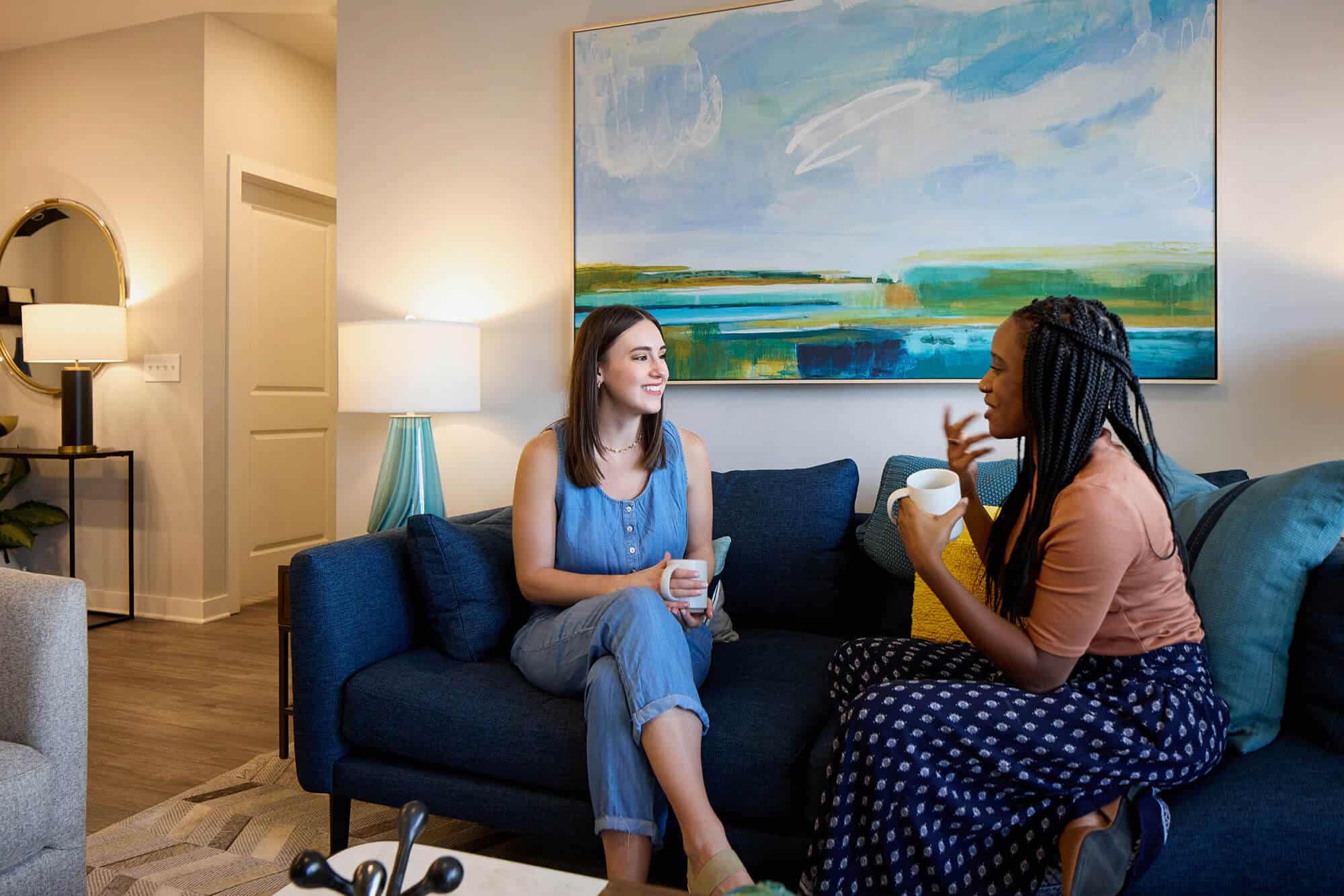Two people talking on a blue couch in an apartment at Story Wesley Chapel luxury apartments.